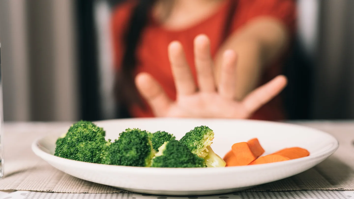 Child at the table refusing to eat vegetables
