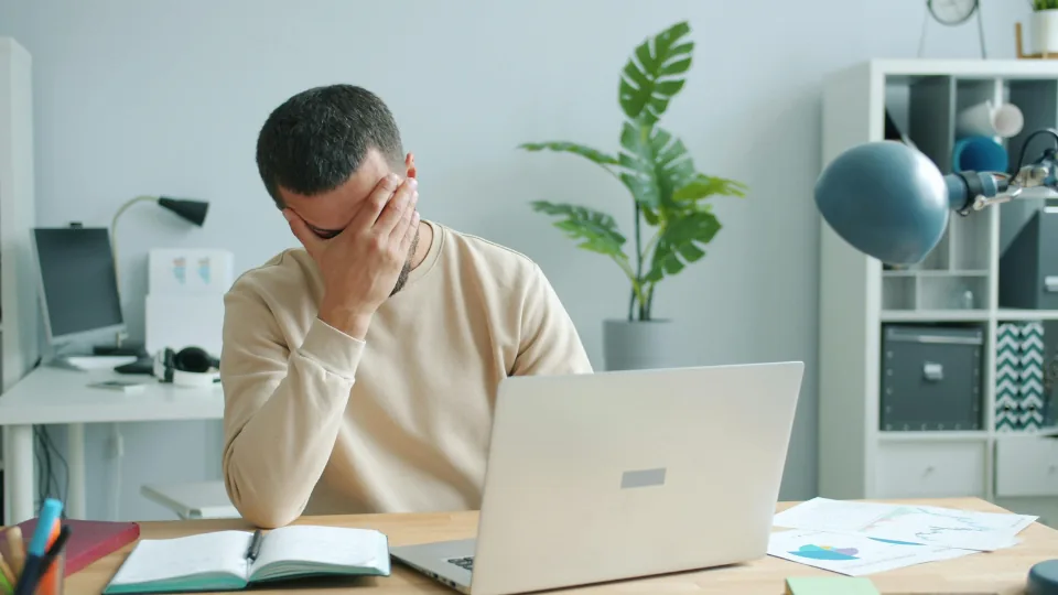 Tired man at a laptop rubbing his eyes
